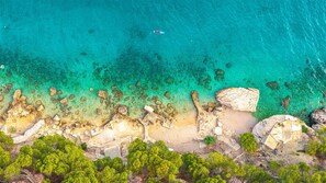 A coastal landscape with clear turquoise waters, rocky shoreline, and dense green vegetation. - Villa Aurea Beachfront & Spa with Heated Pool (Mimice)