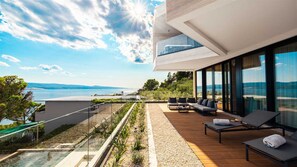 A modern outdoor lounge area with a view of the sea, furnished with sofas and a table. - Villa Aurea Beachfront & Spa with Heated Pool (Mimice)