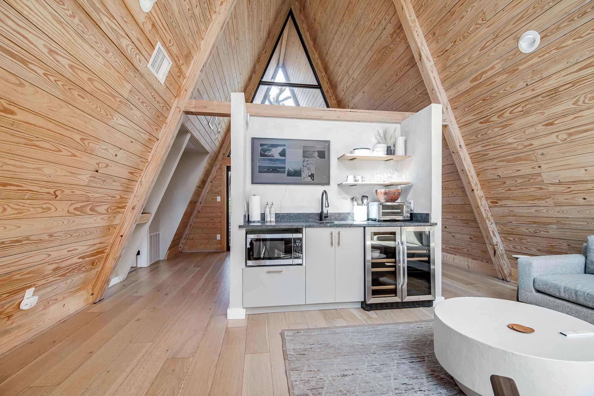 A compact kitchen with modern appliances, a dining area with a round table, and a loft bedroom with a skylight.