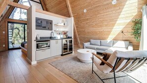A modern loft-style room with a kitchen, dining area, and seating space. - A-Frame Ranch: Pecan Treehouse with Shared Pool (Fredericksburg)