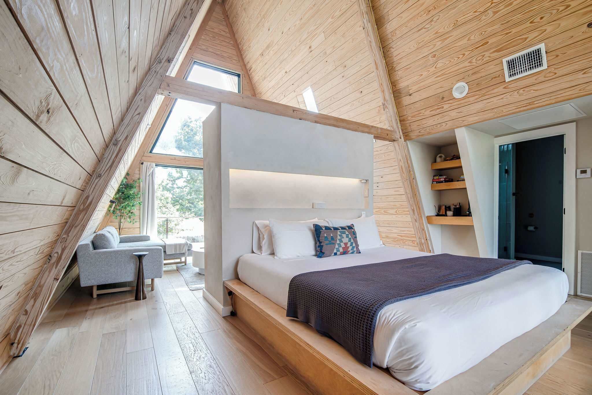 A bedroom with a large bed, a bedside table, a chair, and a window.