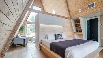 A bedroom with a large bed, a bedside table, a chair, and a window.