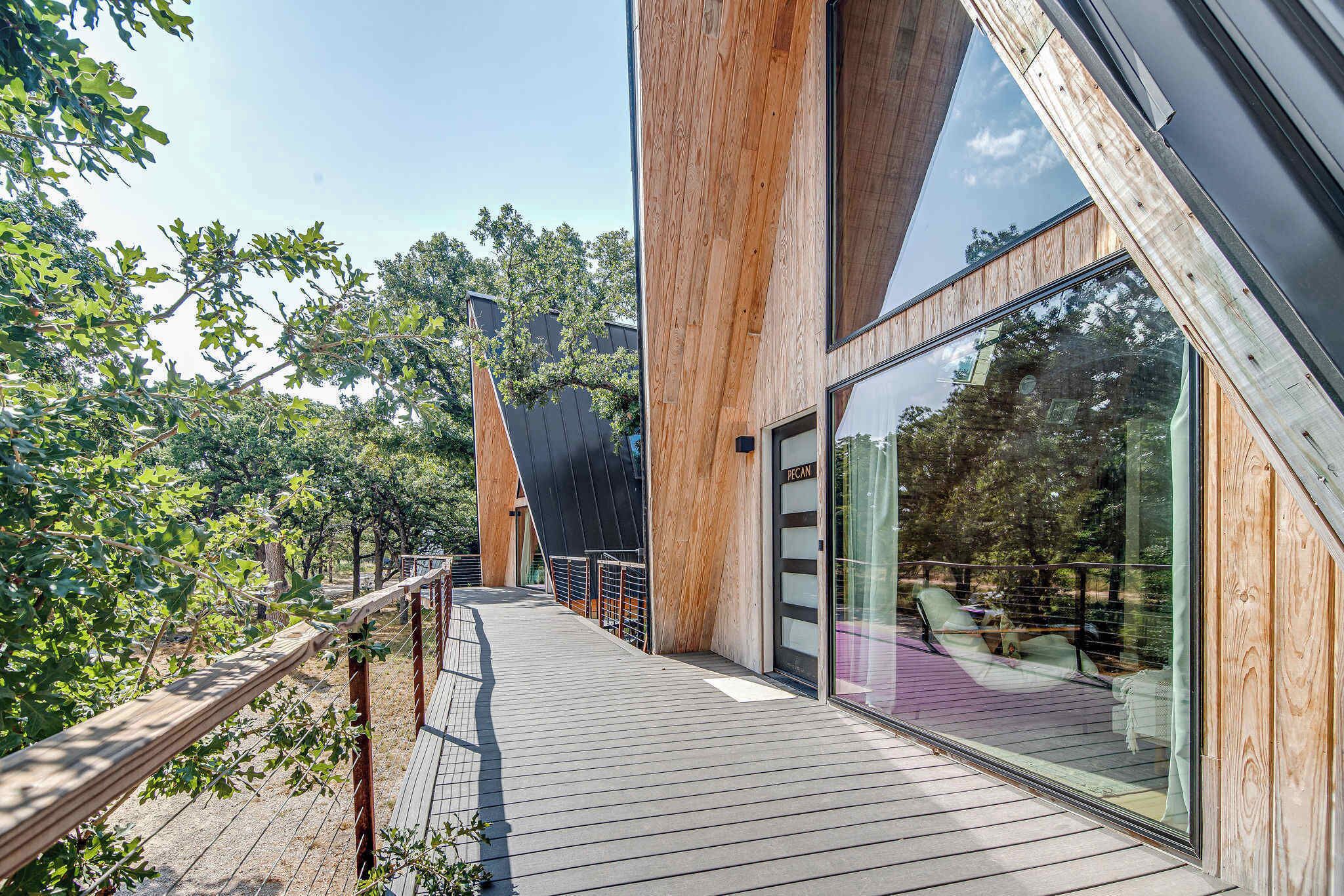 A wooden deck with a glass door leading to an outdoor seating area.
