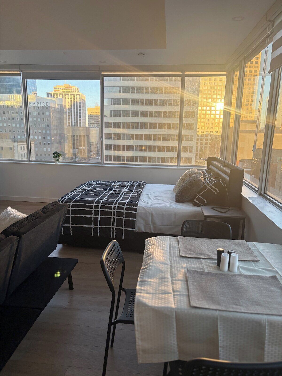 Una camera da letto moderna con un letto, una scrivania e vista sugli edifici della città.