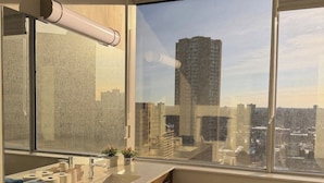 A modern bathroom with a large window, a sink with a mirror, and a wooden cabinet.