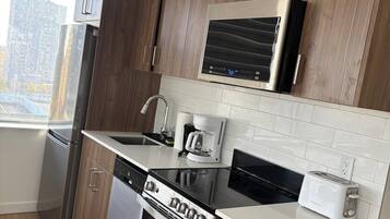 A modern kitchen with stainless steel appliances, wooden cabinets, and a window providing a view of the city.