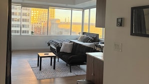 A modern bedroom with a large window, a bed, a desk, and a chair.
