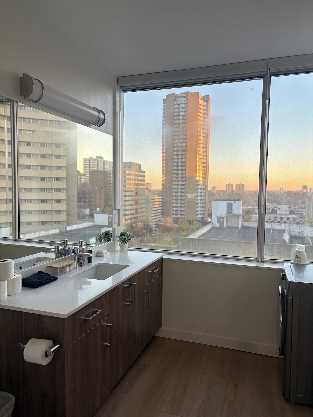 Una cucina moderna con un'ampia finestra, un lavello, pensili e vista sulla città.