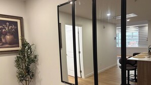 A room with a large mirror, a potted plant, and a painting on the wall. - One-Bedroom Executive Stay | Central & Convenient (Edmonton)