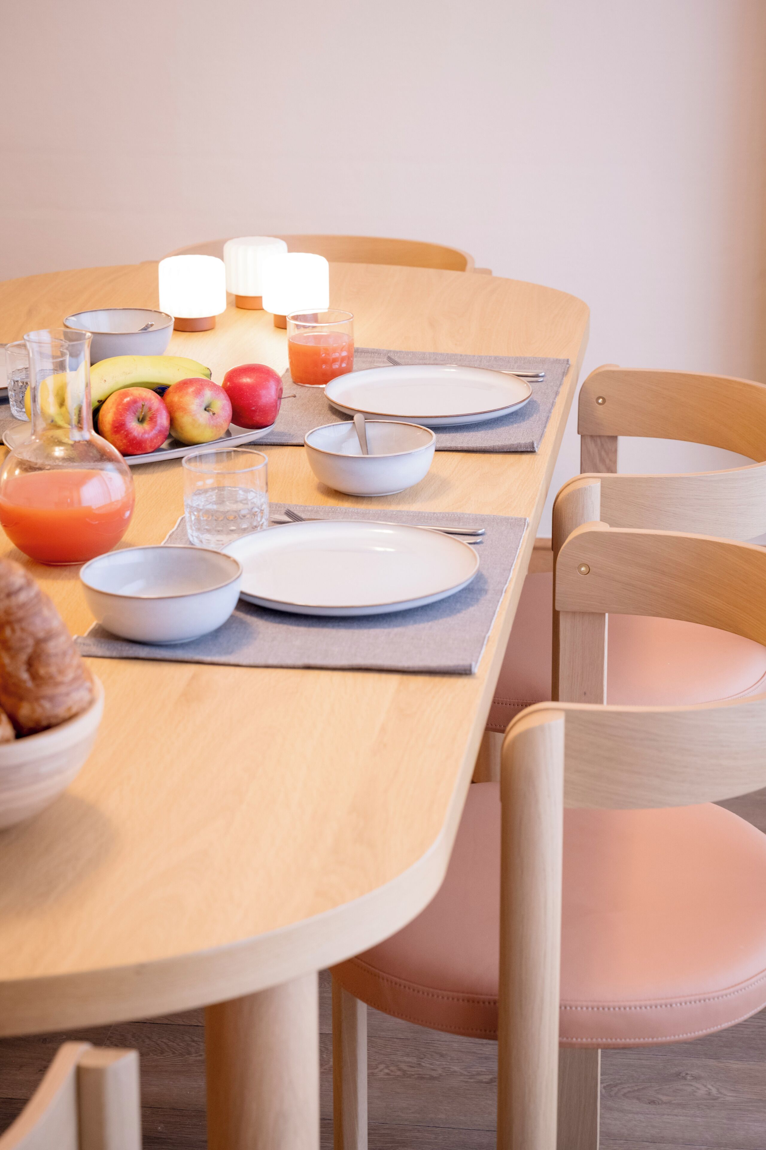 A dining table set with plates, bowls, glasses, and a fruit bowl.