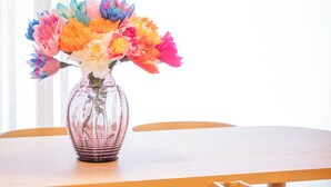 Une table à manger ornée d’un vase rempli de fleurs en papier aux couleurs vives.