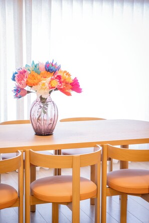 A dining table with a vase of colorful paper flowers. - La Petite Crevette: Beach and Charm in De Haan (De Haan)