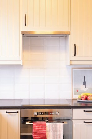 Cocina con armarios blancos, horno de acero inoxidable y salpicadero de azulejos.