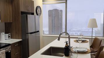 A modern kitchen with a central island, stainless steel appliances, and a view of a cityscape through large windows.