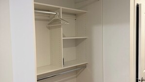 Ein begehbarer Kleiderschrank mit offenen Türen, einer Kleiderstange und einem Schuhregal.