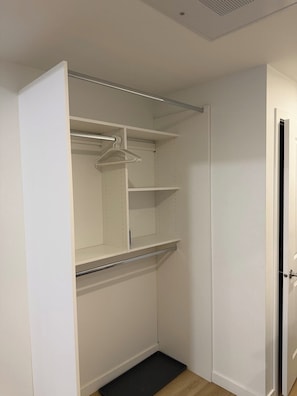 A walk-in closet with open doors, a hanging rod, and a shoe shelf. - Downtown Gem 2BR Apartment with Stunning City View (Edmonton)