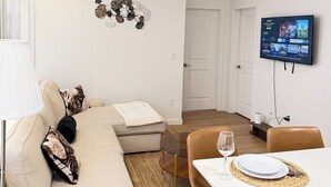 Ein modernes Wohnzimmer mit einer Couch, einem Couchtisch und einem an der Wand befestigten Fernseher.