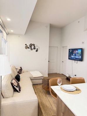 A modern living room with a sofa, a coffee table, and a TV mounted on the wall. - Downtown Gem 2BR Apartment with Stunning City View (Edmonton)