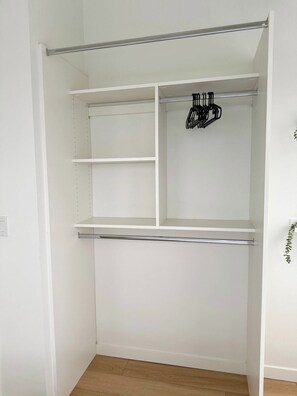 A white closet with multiple shelves and hanging space. - Downtown Gem 2BR Apartment with Stunning City View (Edmonton)