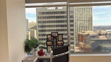 A modern office space with a desk, chair, and a large window offering a city view.
