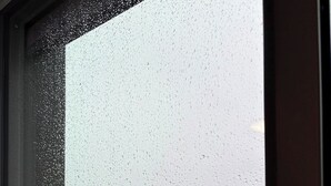 A view through a window with raindrops, featuring a parking lot with several cars and a bridge in the background. - Executive Studio Near Rogers Place” (Edmonton)