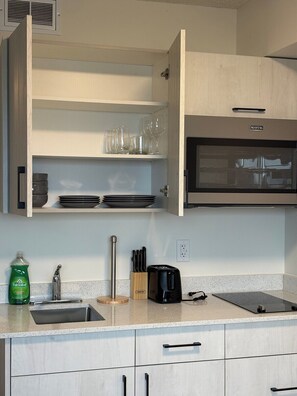 A kitchen with a built-in oven, a sink, and a countertop with a knife block and a toaster. - Executive Studio Near Rogers Place” (Edmonton)