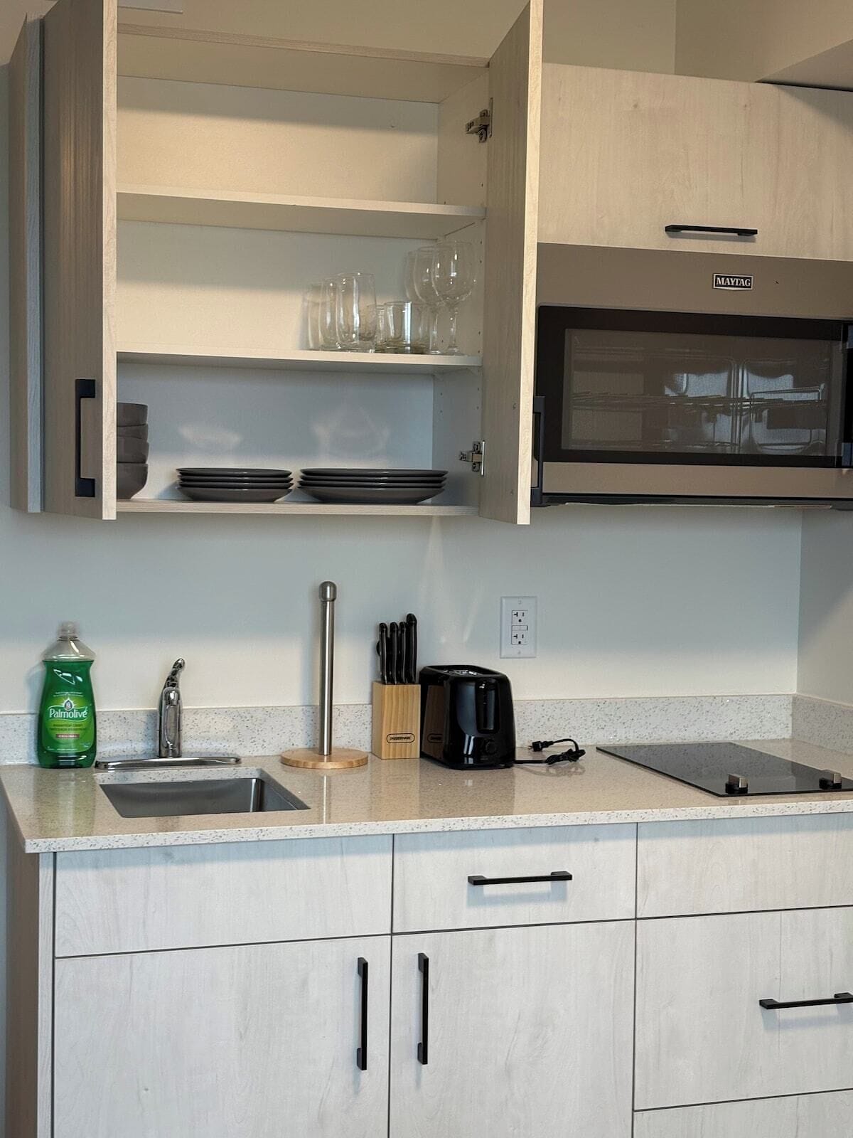 A kitchen with a countertop, a sink, a dish rack, a toaster, and a cabinet with a Maytag oven.