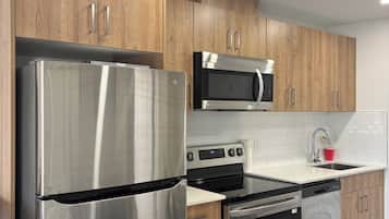 A modern kitchen with stainless steel appliances, wooden cabinets, and a white countertop.