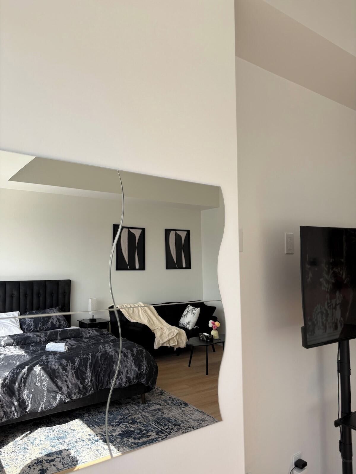 A bedroom with a bed, a nightstand, a lamp, and a television.