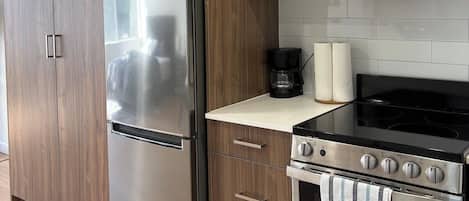 Une cuisine moderne dotée d’appareils électroménagers en acier inoxydable, de meubles en bois et d’une cuisinière noire.