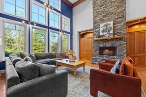 A spacious living room with a stone fireplace, large windows, and a cozy seating area. - Cedar Peak - Hot Tub, Sauna, Theater, Sleeps 24 (Cheatham County)