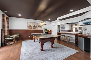 A billiards table in a room with a kitchen area, a bar, and a seating area with a view of the outdoors. - Cedar Peak - Pool, Hot Tub & Gym, Sleeps 24 (Cheatham County)