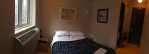 A small, single-bed room with a radiator, a window, and two framed pictures on the wall. - Queen West Jazz Stay (Toronto)