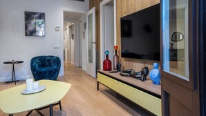A modern living room with a sofa, a coffee table, a TV, and a console table with decorative items. - Design Sun and Rooftop Wi-Fi Fast Sagrada Familia (Barcelona)