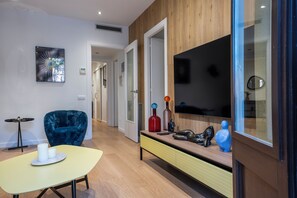Ein modernes Wohnzimmer mit einer Couch, einem Couchtisch, einem Fernseher und einem Konsolentisch mit Dekorationselementen.