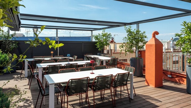 An outdoor patio with tables and chairs, a large planter, and a view of the cityscape. - Design Sun and Rooftop Wi-Fi Fast Sagrada Familia (Barcelona)