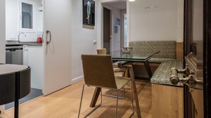 A modern kitchen with a built-in dishwasher, a dining area with a glass table and metal chairs, and a patterned bench. - Design Sun and Rooftop Wi-Fi Fast Sagrada Familia (Barcelona)