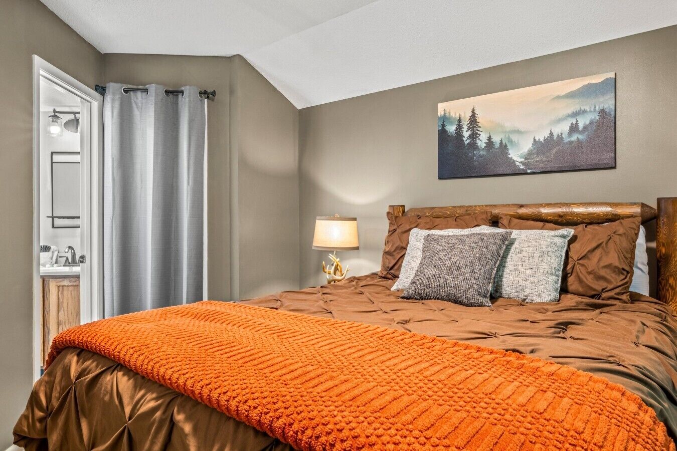 Ein Schlafzimmer mit einem Bett, einem Gemälde, einem Nachttisch und einer Lampe.