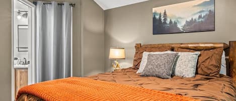 Une chambre à coucher avec un lit, un tableau, une table de chevet et une lampe.