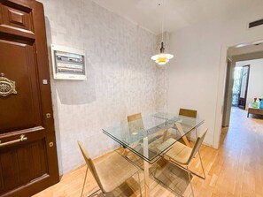 A dining area with a glass table and chairs, a wooden door, a wall-mounted light fixture, and a framed certificate on the wall. - Nomad friendly • Wi-Fi Fast • Rooftop • Center BCN (Barcelona)