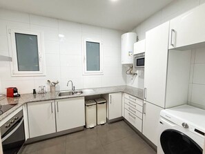 A modern kitchen with white cabinets, a built-in oven, a microwave, and a washing machine. - Nomad friendly • Wi-Fi Fast • Rooftop • Center BCN (Barcelona)