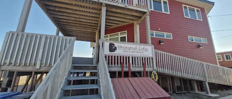 A two-story building with a sign for Umingmak Lodge, featuring a wooden staircase and a red exterior.