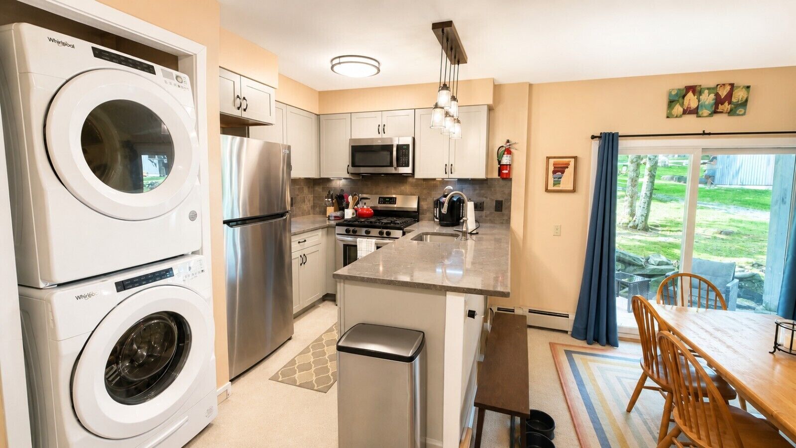 A compact kitchen with a built-in washer and dryer, stainless steel appliances, and a dining area with a view of the outdoors.