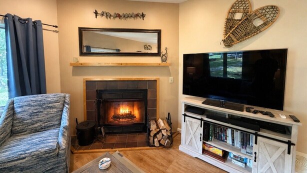 A living room with a fireplace, a television, and a bookshelf. - 7 minutes from the Killington Base Lodge and seconds away from the best restaurants and nightlife! (Killington)