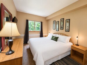 A hotel room with a large bed, a bedside table with a lamp, a nightstand, and a window with curtains. - 7 minutes from the Killington Base Lodge and seconds away from the best restaurants and nightlife! (Killington)