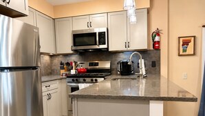 A modern kitchen with stainless steel appliances, a granite countertop, and white cabinetry. - 7 minutes from the Killington Base Lodge and seconds away from the best restaurants and nightlife! (Killington)