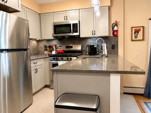 A modern kitchen with stainless steel appliances, a granite countertop, and white cabinetry. - 7 minutes from the Killington Base Lodge and seconds away from the best restaurants and nightlife! (Killington)