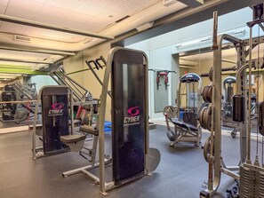Ein Fitnessstudio mit verschiedenen Trainingsgeräten, darunter eine Cybex International Maschine, Gewichtbänke und Kurzhanteln.