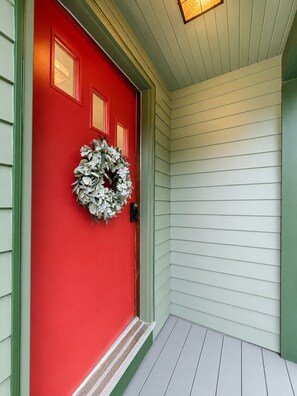 A red door with a wreath, a green trim, and a light-colored exterior wall. - Near Killington & Woodstock | Game Room, Fireplace (Bridgewater)