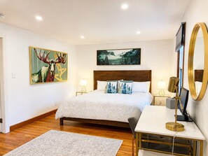 A bedroom with a bed, bedside tables, a desk, a chair, a large mirror, and two paintings on the wall. - Near Killington & Woodstock | Game Room, Fireplace (Bridgewater)